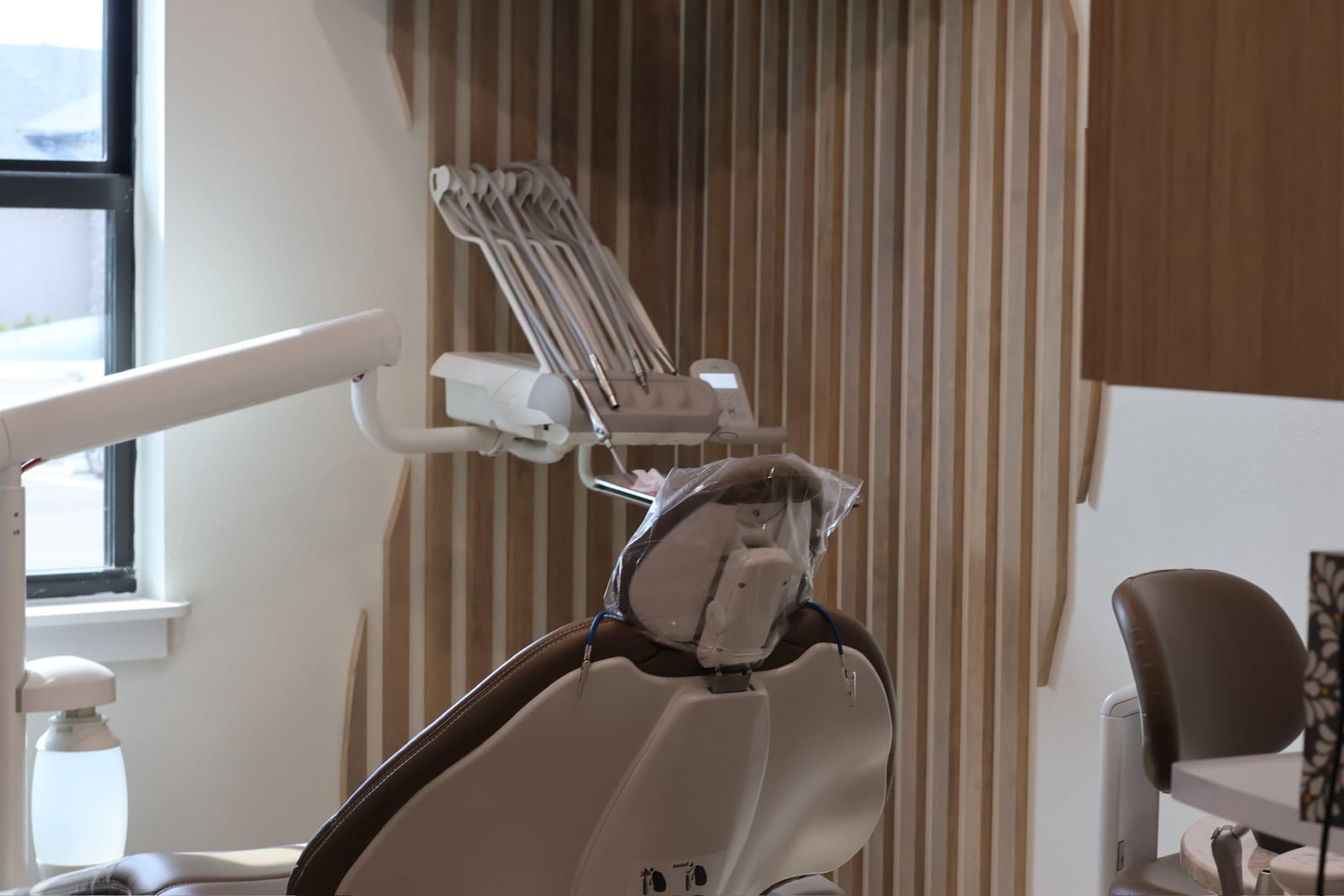 A private treatment room at Omni Dental Studio with a dental chair, natural light and a wood-slat wall